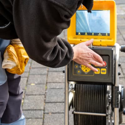 A professional drain unblocker looking at a drain camera to view a blockage
