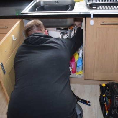 A plumber in Buxton repairing a blocked sink in a house in SK17