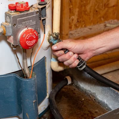 Plumber connecting a hose to a boiler that needs to have a powerflush done to it