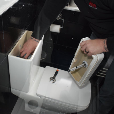 A plumber doing a toilet repair in a house in Buxton